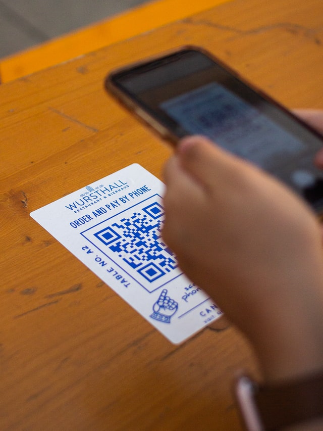 Persona escaneando un código QR en la mesa de un restaurante. 